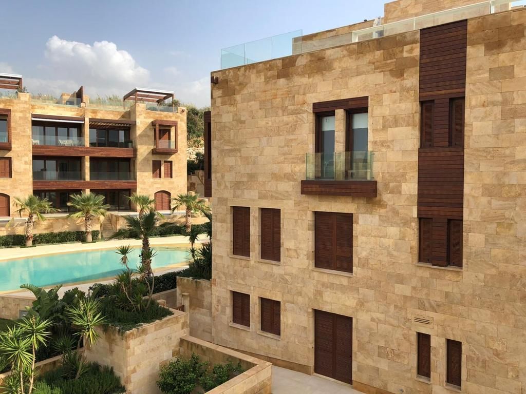 Stone residential façade with timber screens beside a landscaped pool
